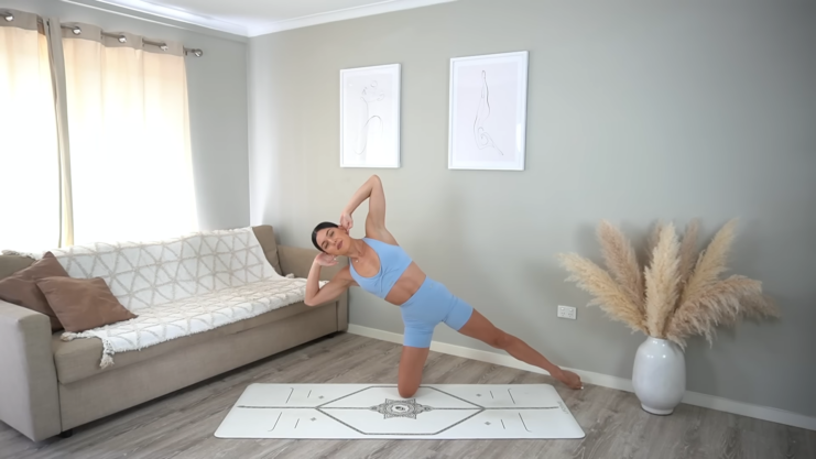 A Woman Practicing a Yoga Pose on A Mat in A Cozy Living Room, Demonstrating Flexibility and Balance