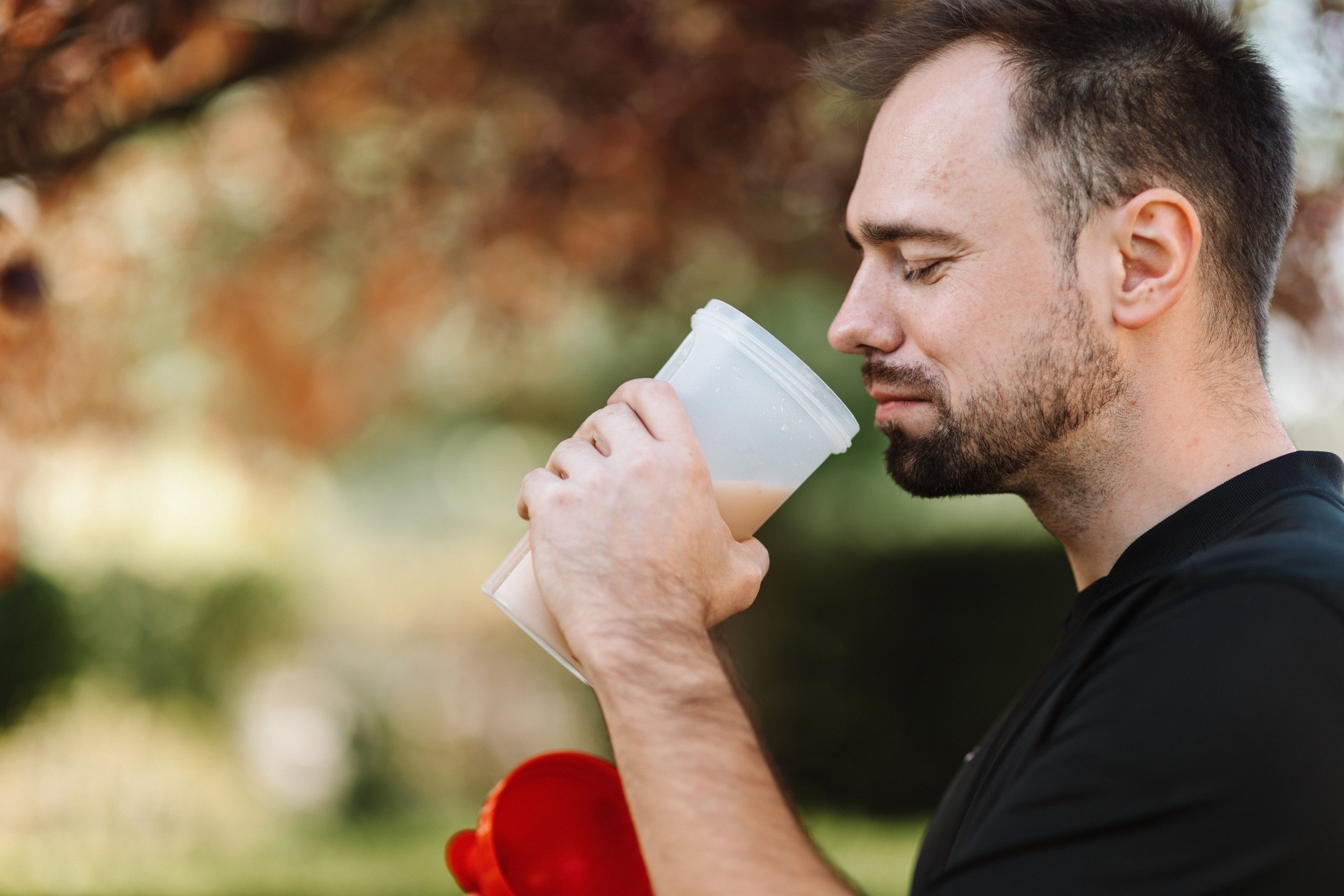 Man drinking a protein shake outdoors after a workout