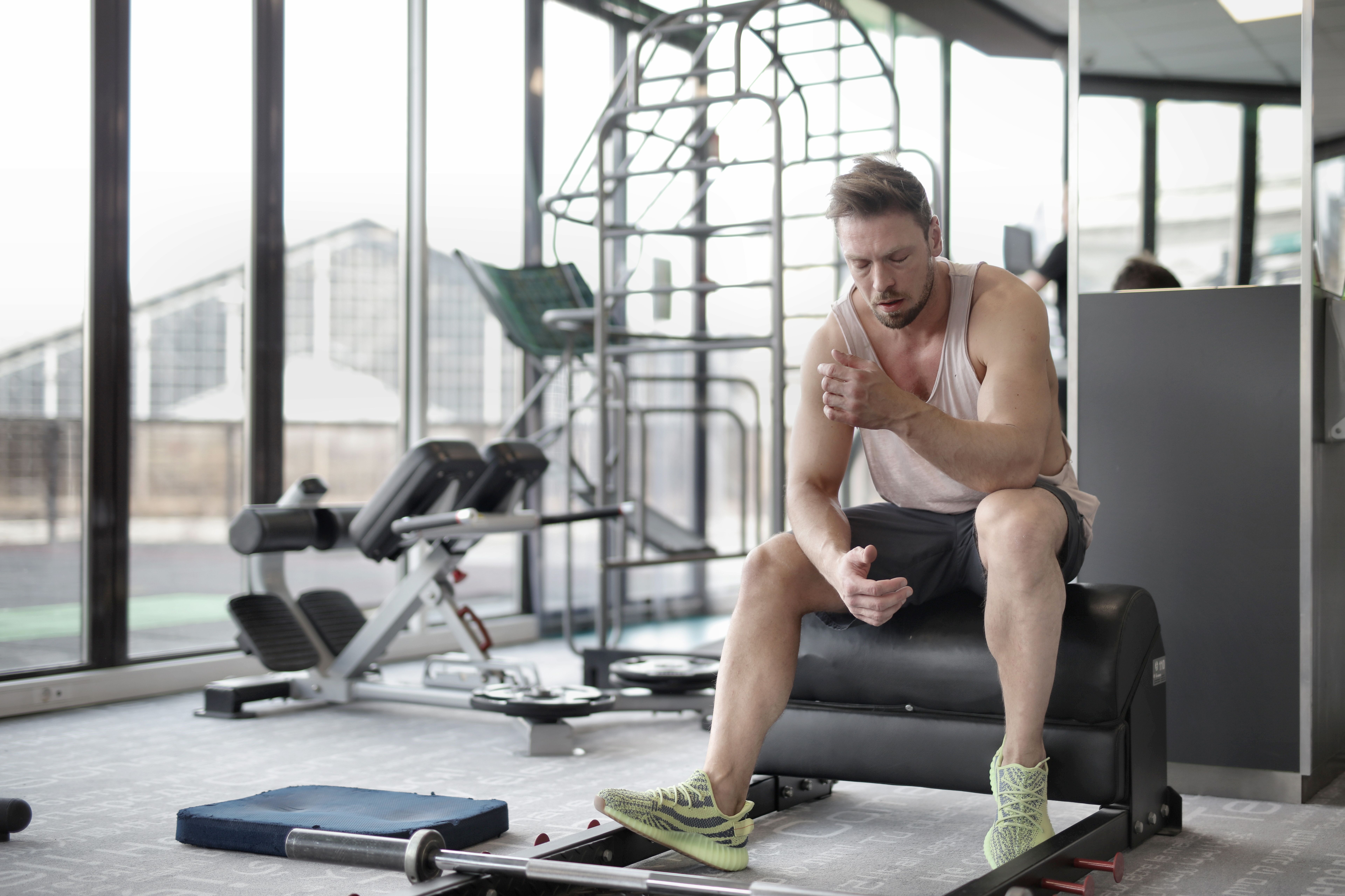 Tired athlete resting on a bench after an intense workout, highlighting the importance of recovery in a sustainable exercise plan
