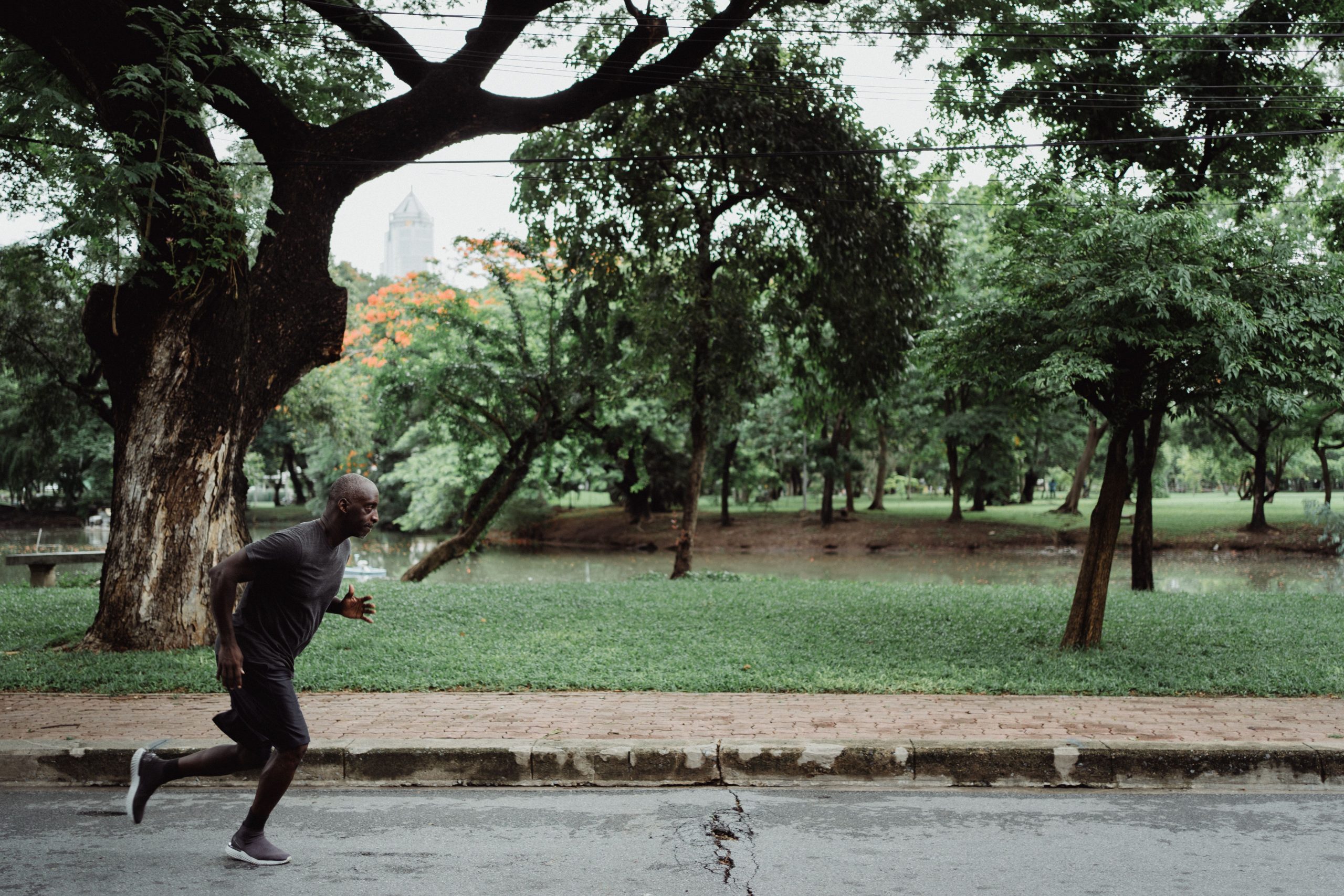 Man jogging on a path in a lush green park as part of a sustainable exercise routine