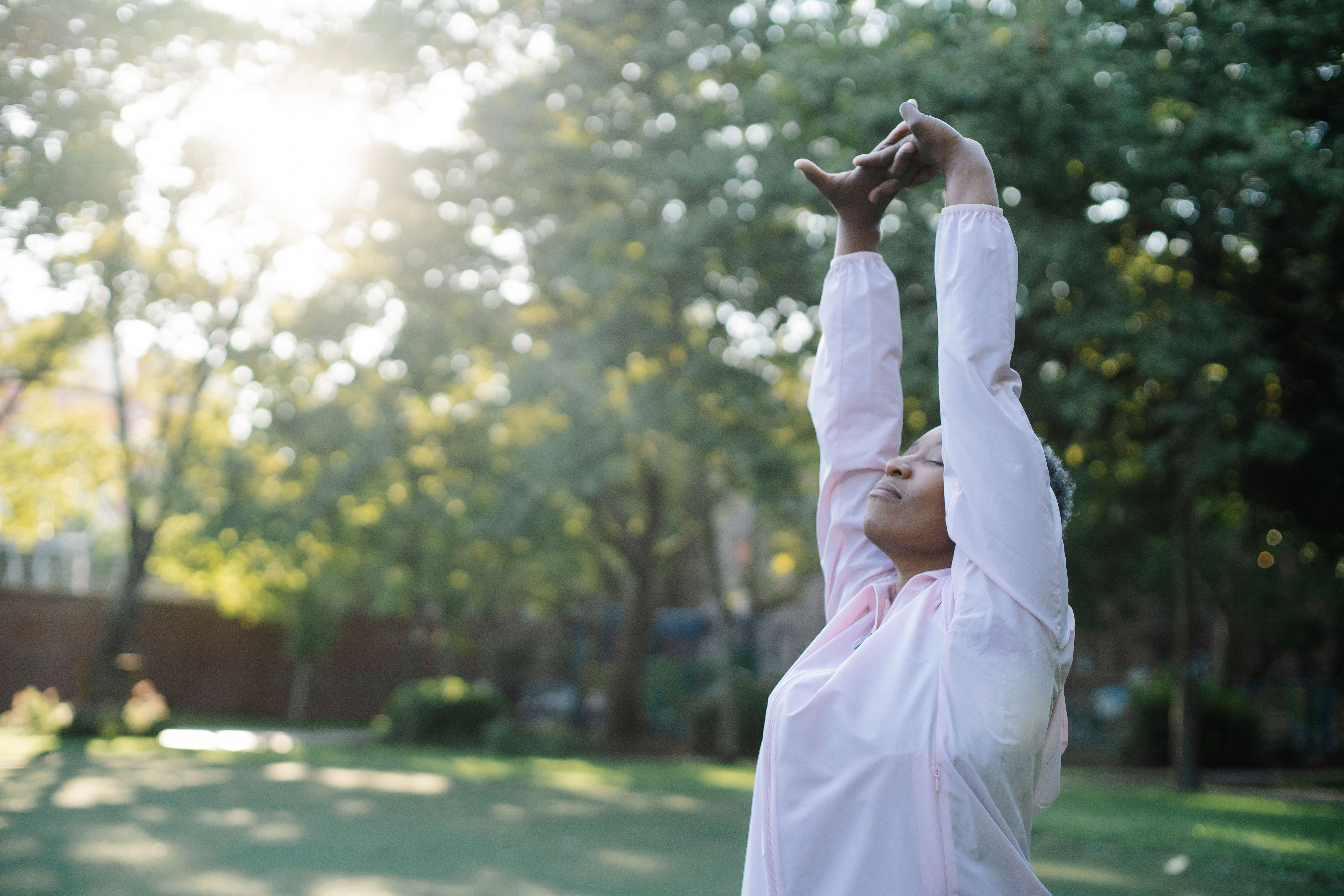 Woman stretching outdoors in a sunlit park, representing consistent long-term exercise habits