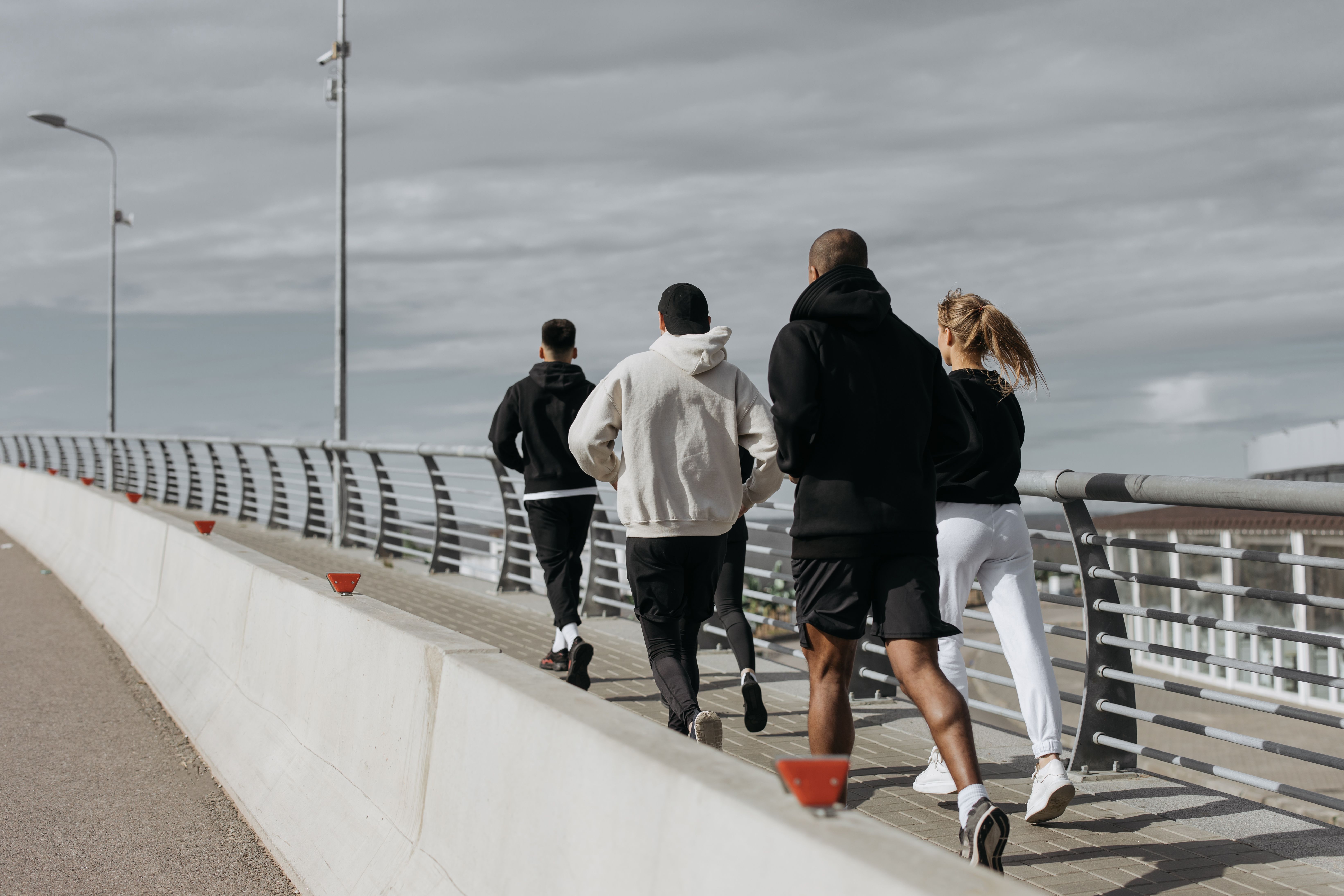 Group of active adults jogging together across a city bridge