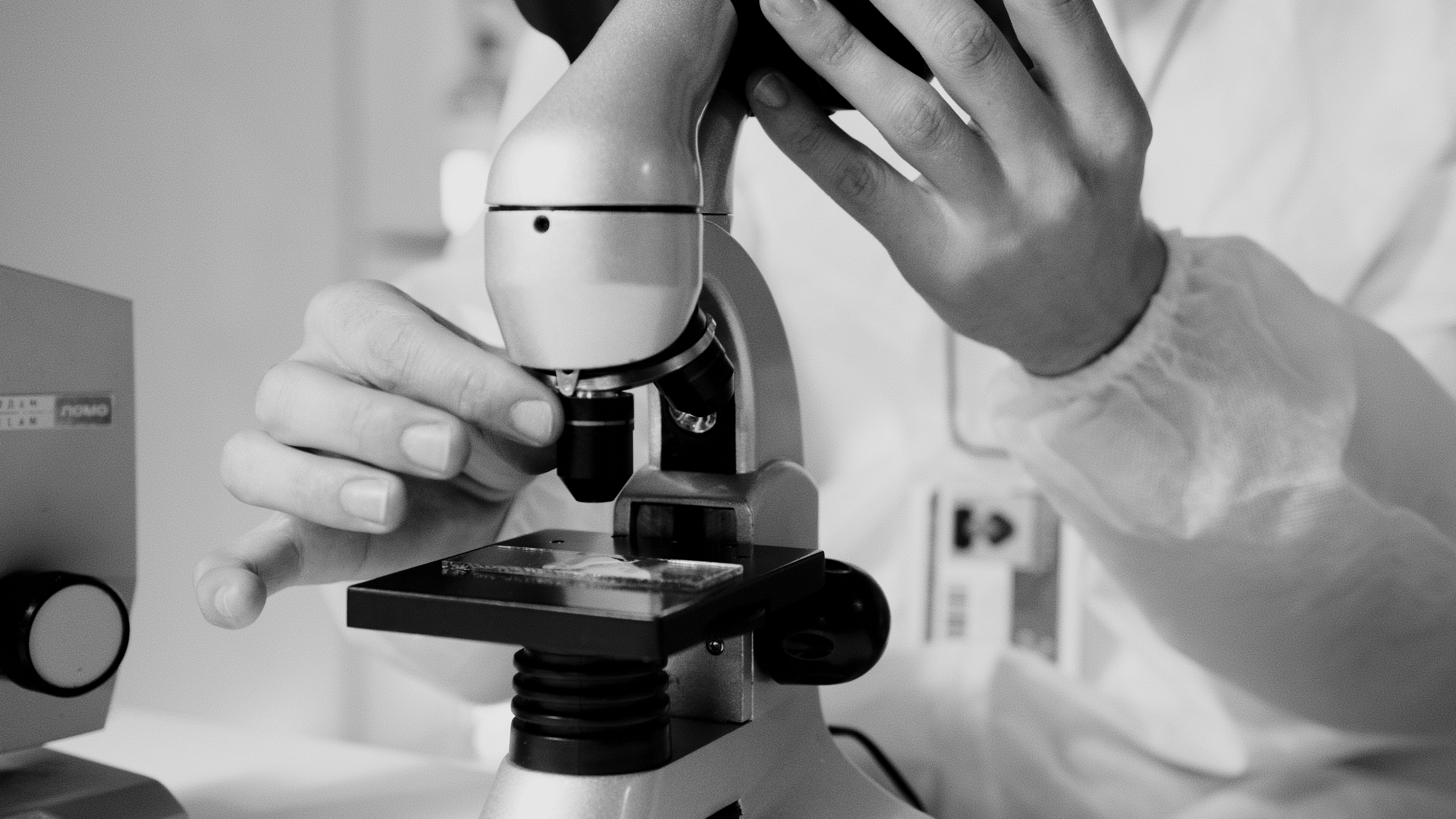 Scientist in a lab coat using a microscope to review antioxidant supplement research