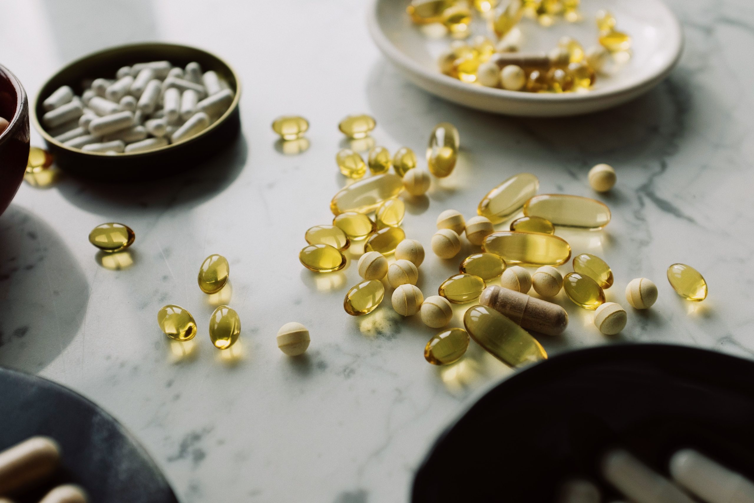 Assorted antioxidant supplement pills and capsules arranged on a marble surface