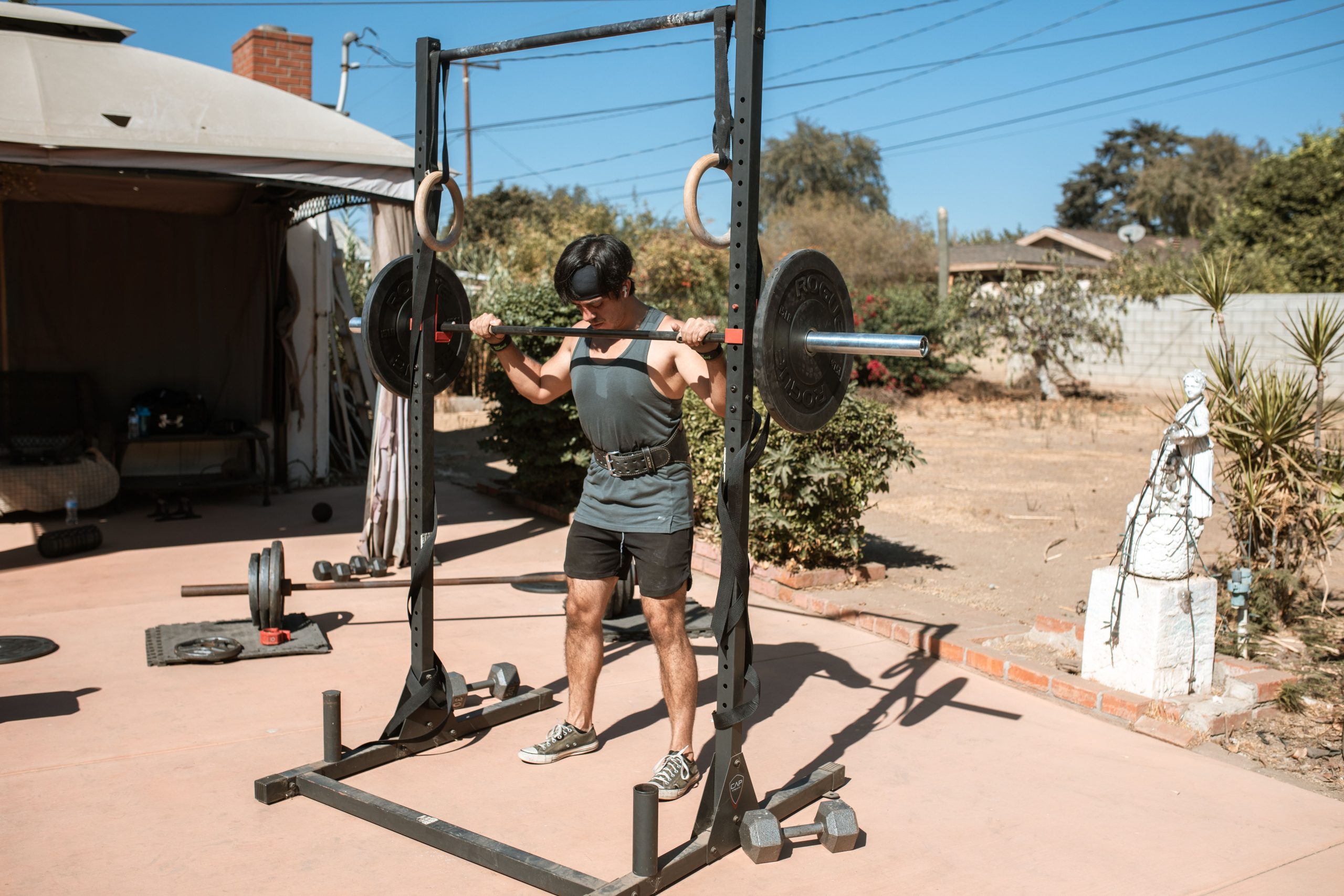 Man doing a barbell squat in an outdoor gym setting for strength training